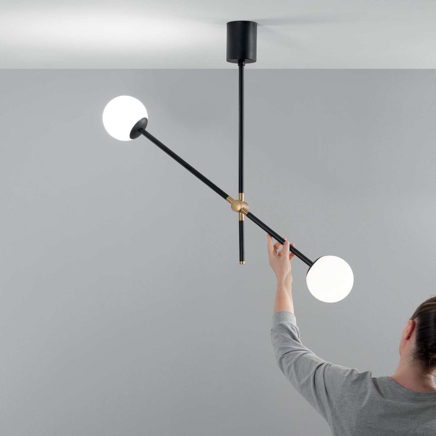 Sospensione ANTITESI con steli orientabili in metallo nero e oro con due diffusori in vetro bianco
